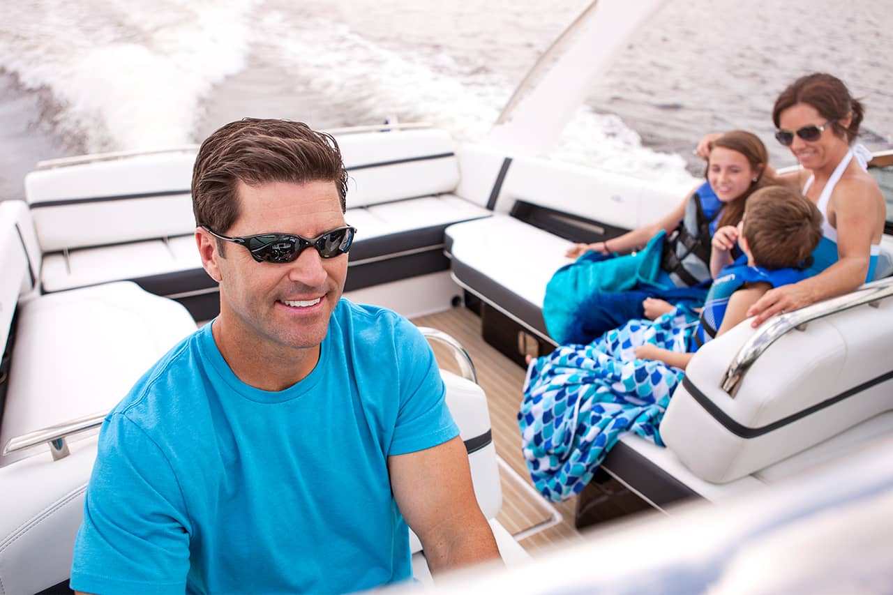 Close up of happy new recreational boat owner driving boat with family 