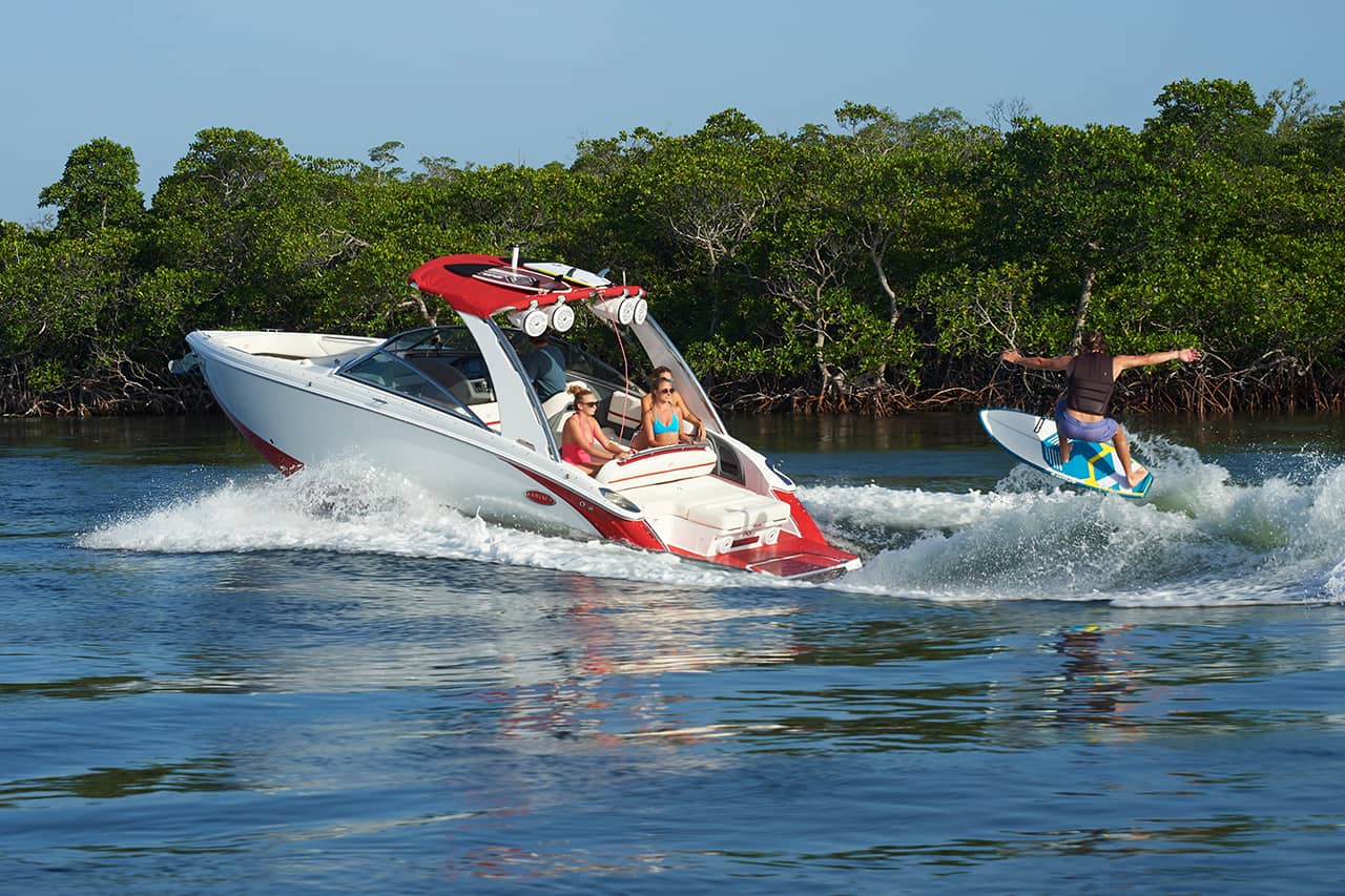 Used boat owner and friends on a personal watercraft watching a wake surfer in tow