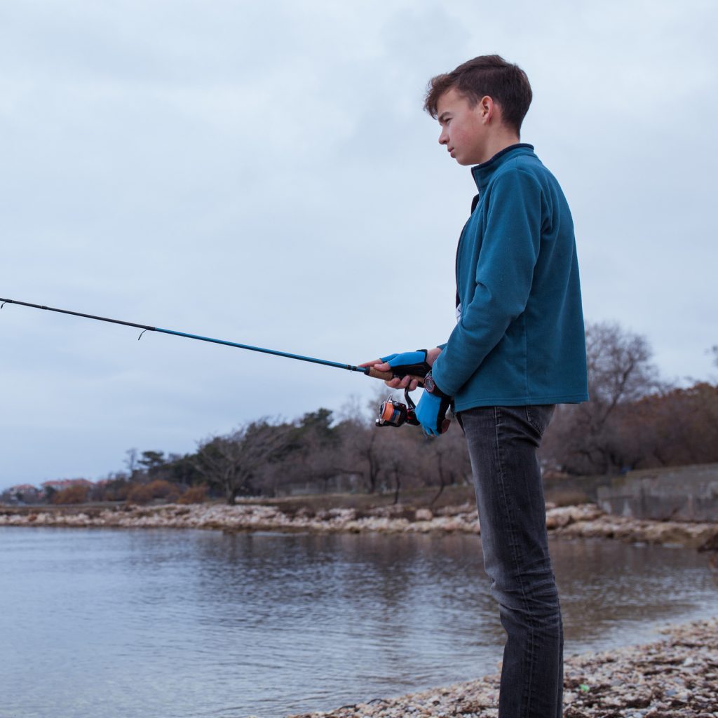 Young bass angler at the edge of a lake